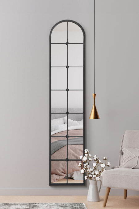 Arched window pane mirror with black frame styled in a softly lit bedroom setting