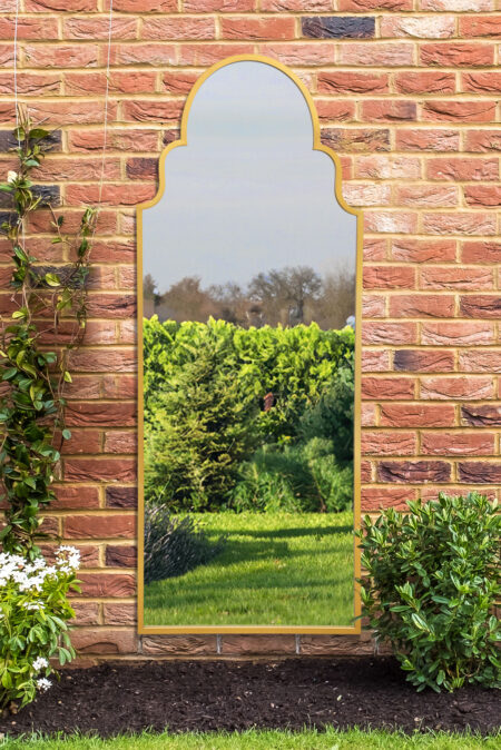 Gold Moorish arch mirror with scalloped frame mounted on an outdoor brick wall