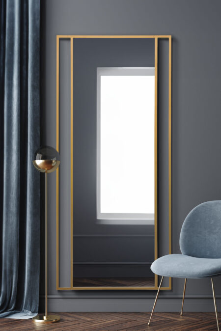 Tall gold split-frame mirror styled in a moody grey living room setting