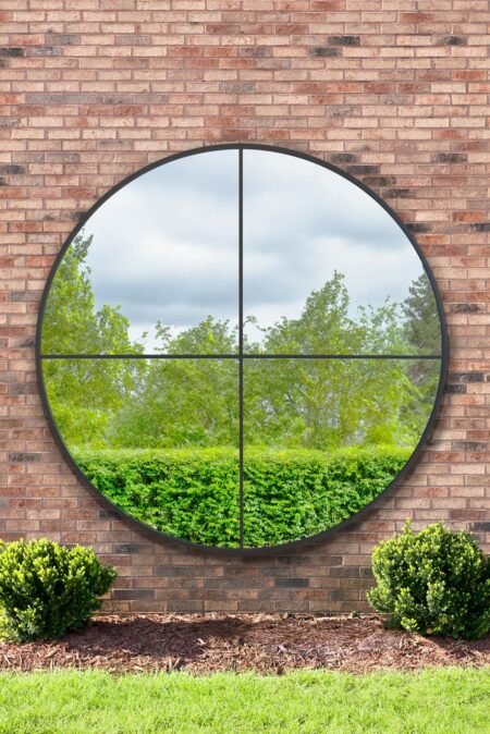 Extra large round quadrant mirror with black mullion frame mounted on a brick garden wall