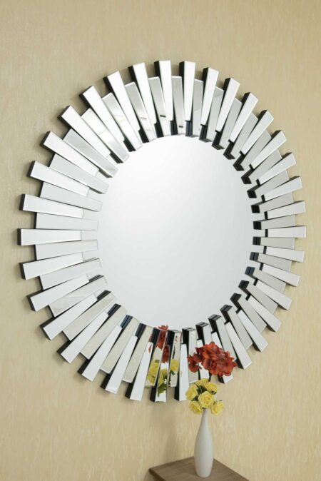 Large round art deco mirror with staggered sunburst frame hung above a flower vase