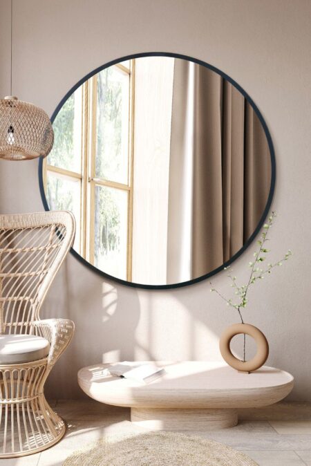 Large round mirror with black metal frame styled in a bright natural living room setting
