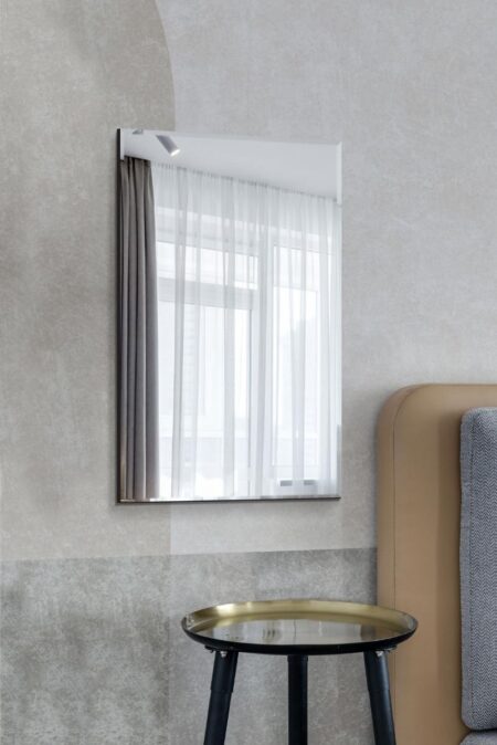 Frameless mirror 120 x 80 hung portrait on a grey wall above a brass side table